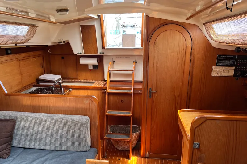 Slide: The Image of 1986 Wauquiez Petorine yacht interior with wooden finish, compact kitchen, and cozy seating area. - 6