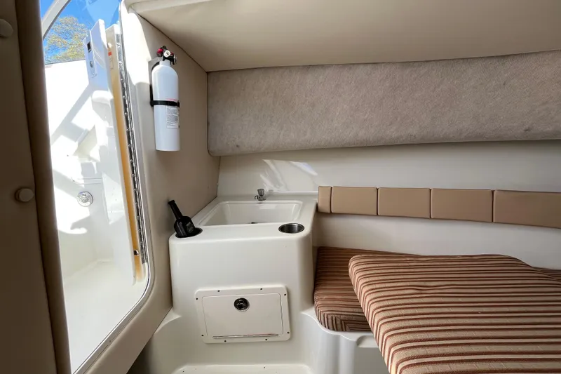 Slide: The Image of 2009 Hydra-Sports 2000 WA cabin interior with sink, fire extinguisher, and striped seating. - 27
