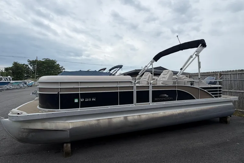 The Image of 2013 Bennington 2375 GCW pontoon boat with canopy, parked on asphalt under cloudy skies. - 1