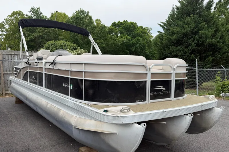 Slide: The Image of 2013 Bennington 2375 GCW pontoon boat parked on pavement with lush greenery background. - 5