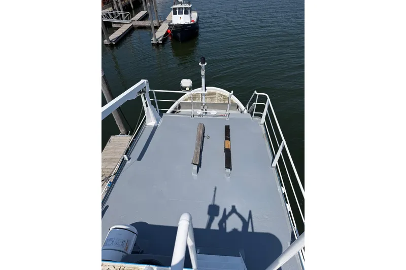 Slide: The Image of 1954 American 70 Tugboat deck, docked at a marina, with clear blue water. - 24