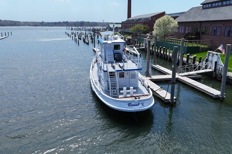 Slide: The Image of 1954 American 70 Tugboat docked at a marina, surrounded by calm water and buildings. - 3