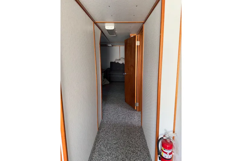 Slide: The Image of Narrow hallway with wooden trim, open door, and fire extinguisher on speckled floor. - 32