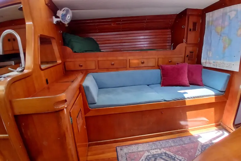 Slide: The Image of Cozy 1981 SKYE 51 yacht interior with wooden cabinetry, blue seating, and world map. - 13