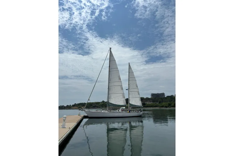 Slide: The Image of Sailboat SKYE 51 from 1981 docked on calm water under a partly cloudy sky. - 2