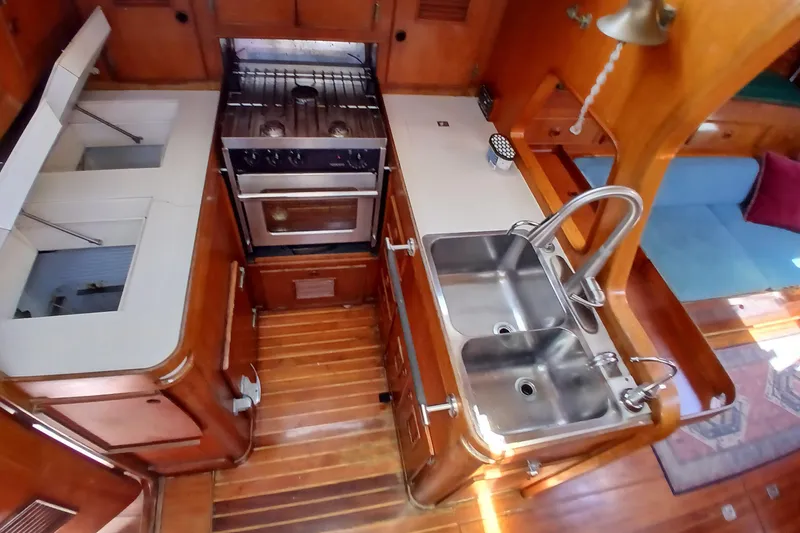 Slide: The Image of 1981 SKYE 51 yacht kitchen with dual sinks, stove, and wooden cabinetry. - 32