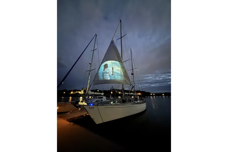 Slide: The Image of Sailboat SKYE 51 (1981) with illuminated sail projection at dusk, docked in a serene harbor. - 4