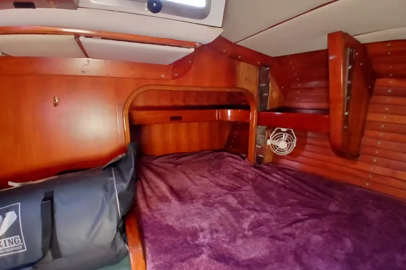Slide: The Image of Cozy cabin interior of 1981 SKYE 51 sailboat with wooden finish and purple bedding. - 49