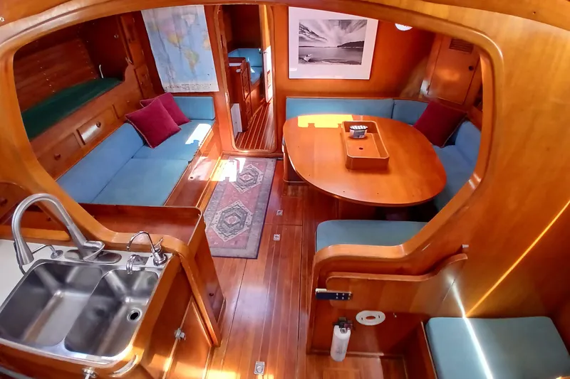 Slide: The Image of Interior of 1981 SKYE 51 yacht with wooden decor, blue seating, and kitchenette. - 6