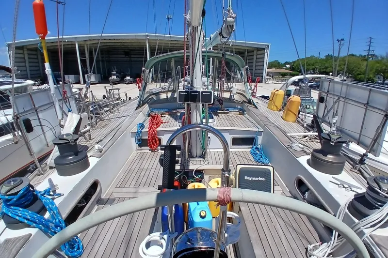 Slide: The Image of 1981 Kaufman Skye 51 sailboat deck with equipment and ropes, docked near a storage facility. - 84