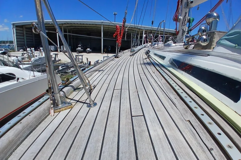 Slide: The Image of Deck view of 1981 Kaufman Skye 51 sailboat in marina, showcasing wooden planks and rigging. - 87