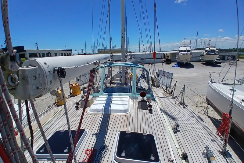 Slide: The Image of 1981 Kaufman Skye 51 sailboat on dry dock, surrounded by other boats under a clear blue sky. - 89