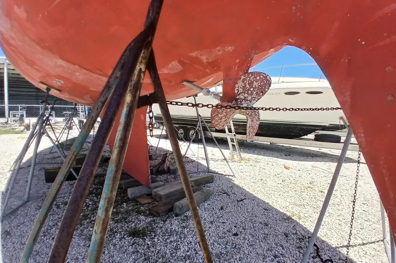 Slide: The Image of 1981 Kaufman Skye 51 sailboat on stands, showing propeller and hull in a boatyard. - 91