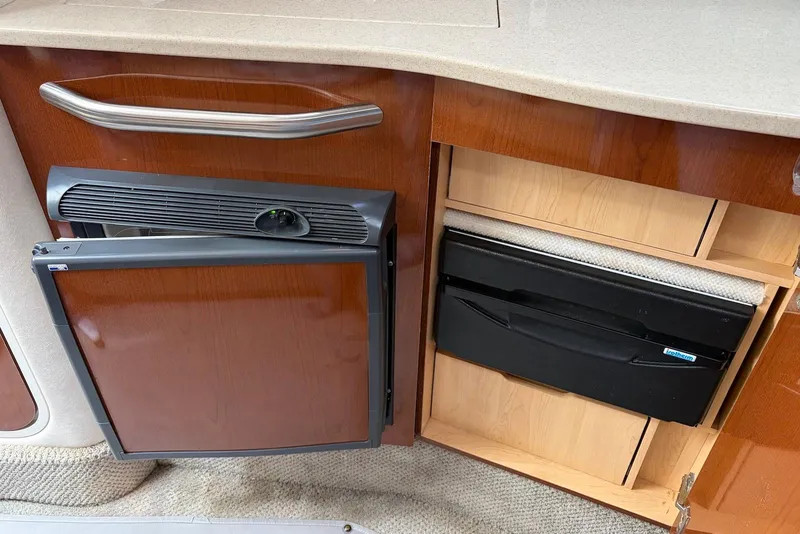 Slide: The Image of 2008 Sea Ray Sundancer 310 interior with wooden cabinetry and compact refrigerator. - 22