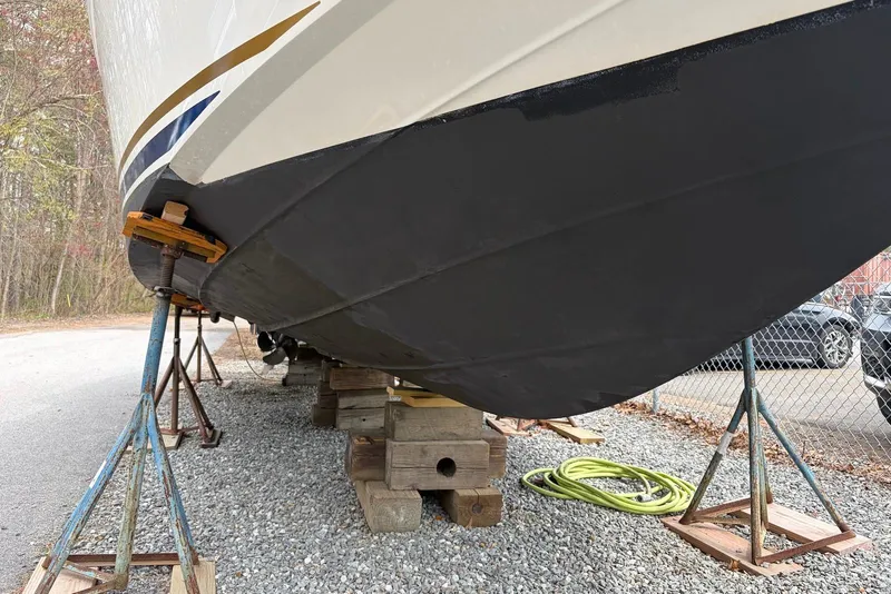 Slide: The Image of 2008 Sea Ray Sundancer 310 boat hull on stands, gravel ground, outdoor setting. - 32
