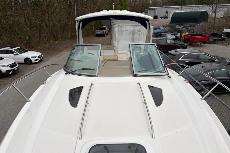 Slide: The Image of 2008 Sea Ray Sundancer 310 boat with open deck and windshield, parked near vehicles. - 5