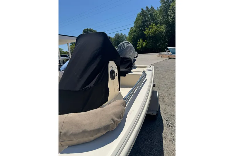 Slide: The Image of 2015 Scout 177 Sport boat with covered seats, parked outdoors on a sunny day. - 17