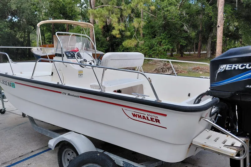 The Image of 2005 Boston Whaler 170 Montauk boat on trailer, surrounded by trees. - 0