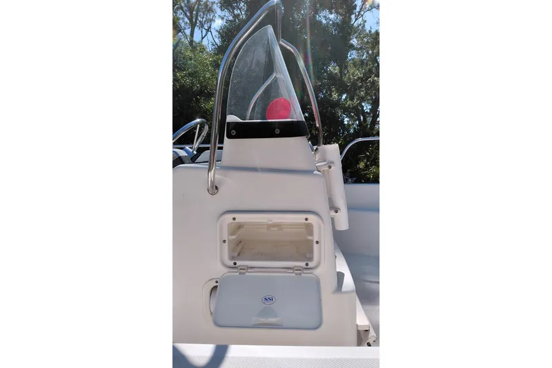 Slide: The Image of 2005 Boston Whaler 170 Montauk console with storage compartment, surrounded by trees. - 9