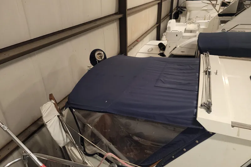 Slide: The Image of 1986 LM 32 boat with blue cover in storage facility. - 12