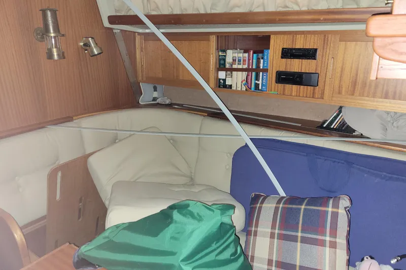 Slide: The Image of Cozy 1986 LM 32 yacht interior with bookshelves, cushions, and wooden paneling. - 22