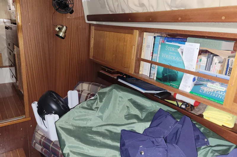Slide: The Image of Cozy cabin interior of 1986 LM 32 boat with books and storage. - 24
