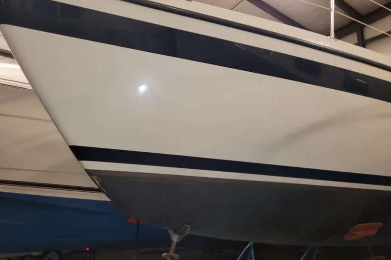 Slide: The Image of 1986 LM 32 boat hull with blue stripe in indoor storage. - 38