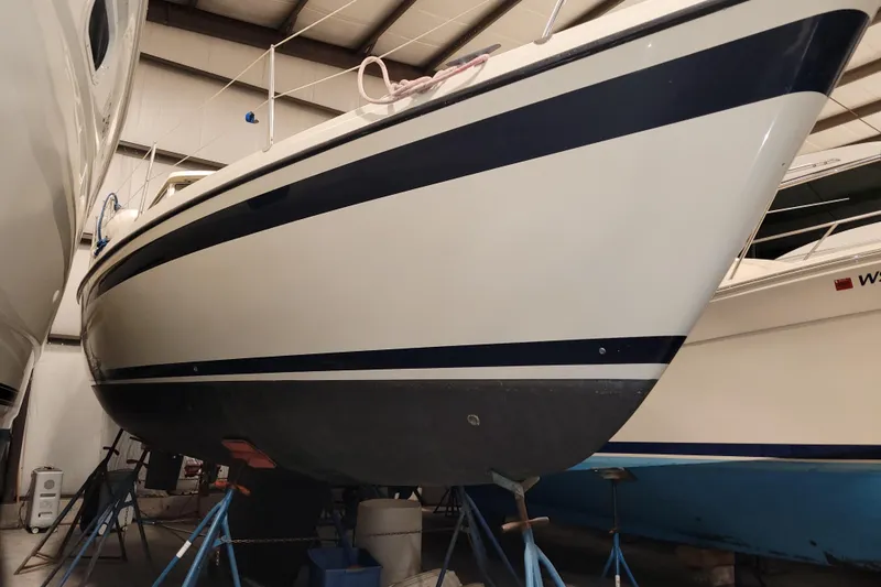 Slide: The Image of 1986 LM 32 sailboat in storage, supported by stands, with a sleek white and blue hull. - 41