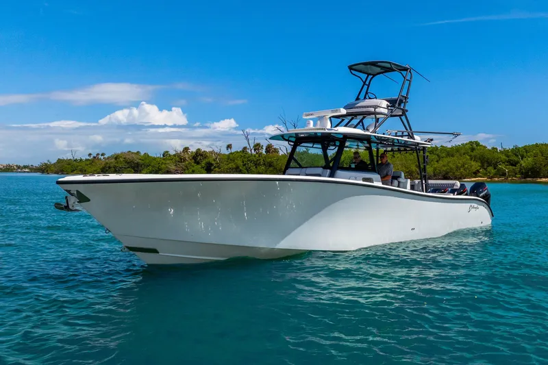 The Image of 2019 Yellowfin 42 Offshore boat on clear blue water, with lush green shoreline. - 1