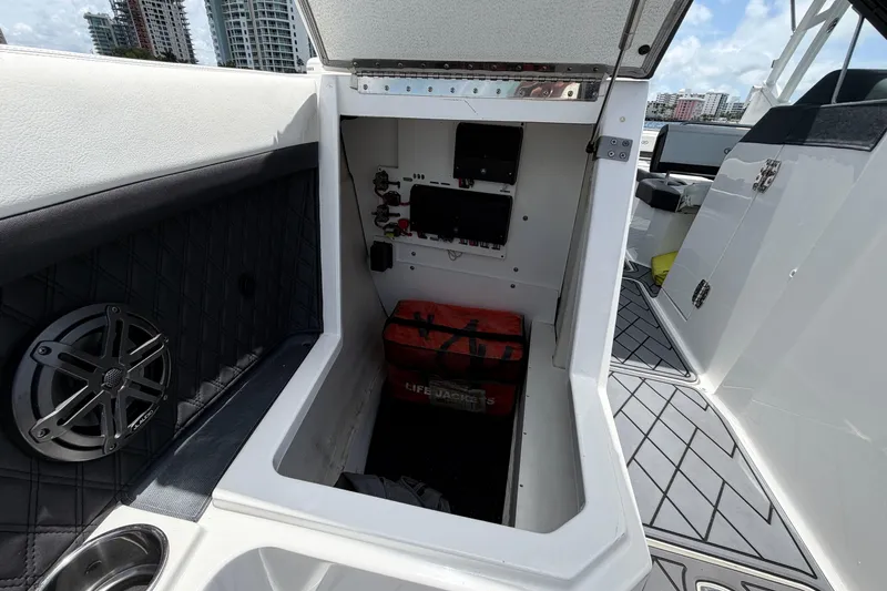 Slide: The Image of 2022 Cobalt R8 Outboard storage compartment with life jackets and speaker, docked near cityscape. - 8