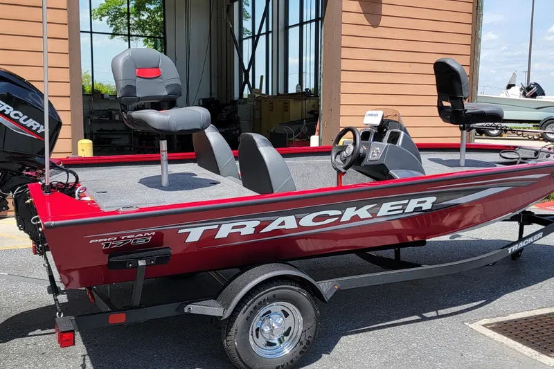 The Image of 2025 Tracker Pro Team 175 boat, red exterior, parked on trailer, featuring Mercury engine. - 1