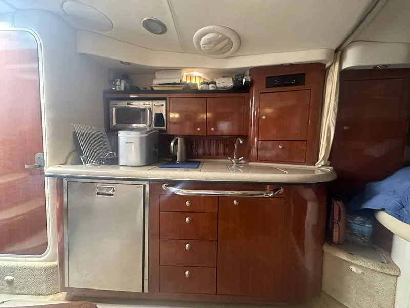 Slide: The Image of 2006 Sea Ray 340 Sundancer galley with wood cabinetry, stainless steel appliances, and sink. - 54