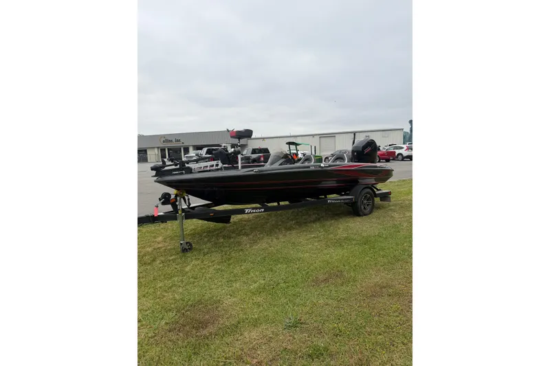 The Image of 2022 Triton 18 TrX bass boat on trailer, parked on grass near industrial buildings. - 1