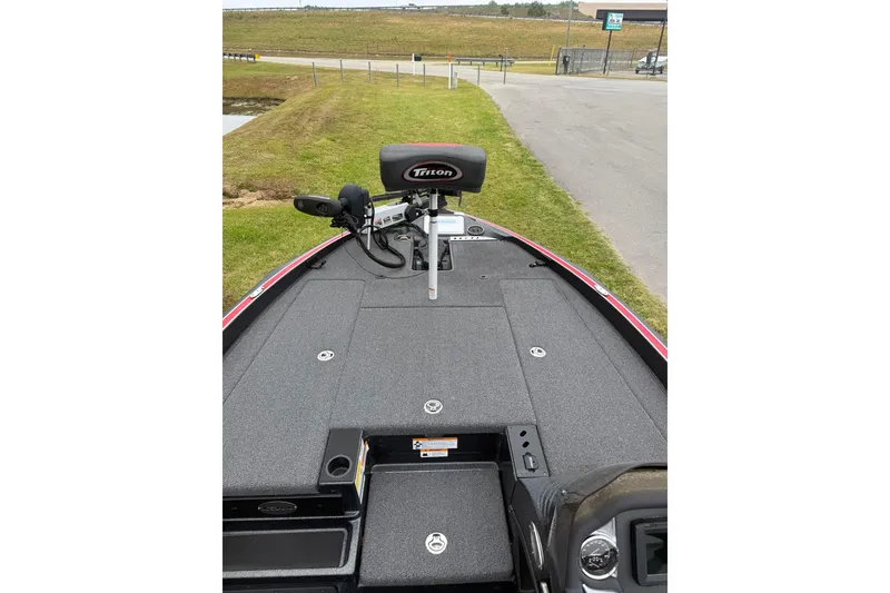 Slide: The Image of 2022 Triton 18 TrX boat deck with trolling motor and seating, parked on grass. - 3