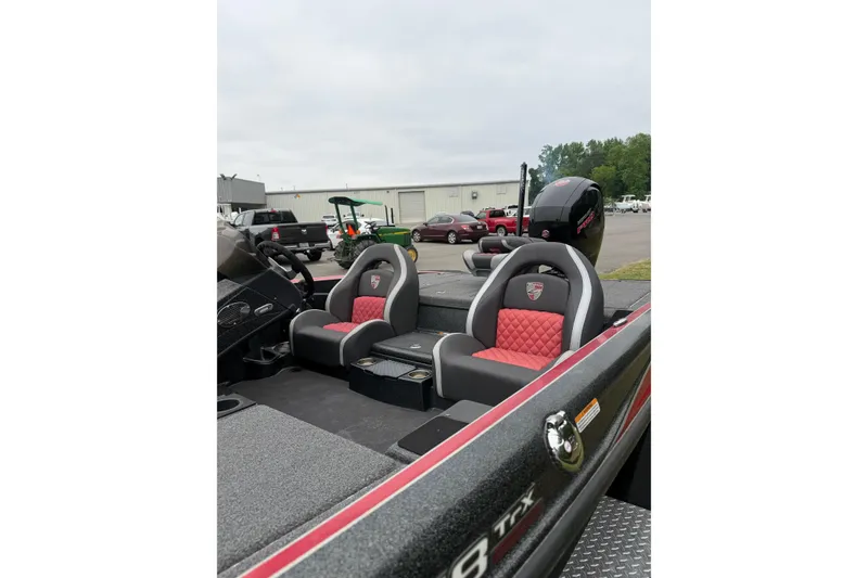 Slide: The Image of 2022 Triton 18 TrX boat interior with red and gray seating, parked outdoors. - 5
