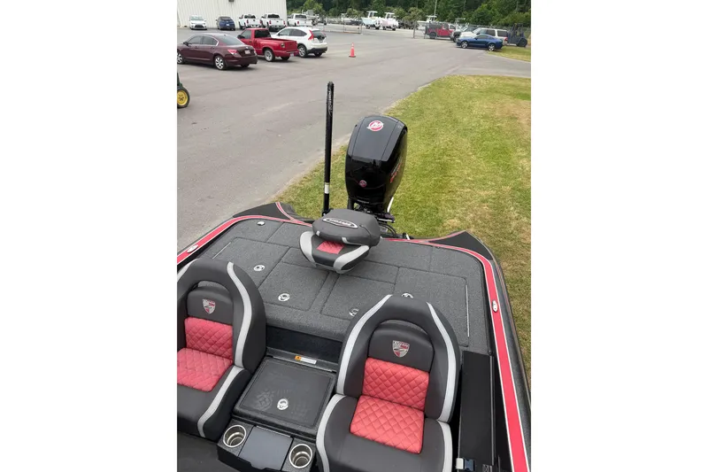 Slide: The Image of 2022 Triton 18 TrX boat with red and black seating, parked near a lot. - 6