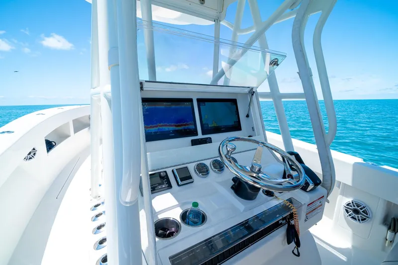 Slide: The Image of 2025 SeaVee 322Z boat helm with modern controls, navigating clear blue ocean waters. - 20
