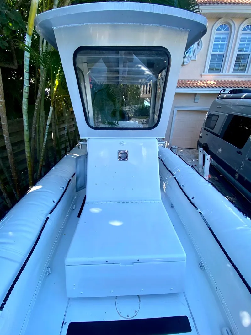 Slide: The Image of 2001 Willard 25 boat with enclosed cabin, docked near a house and vehicle. - 6