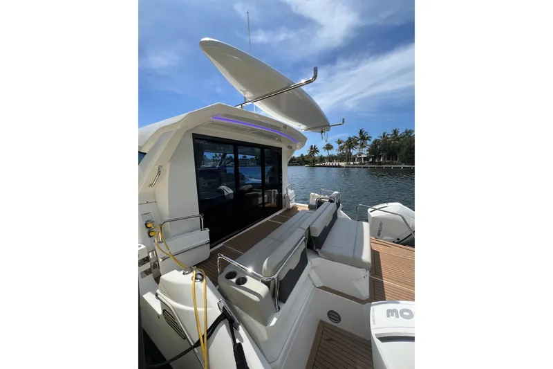 Slide: The Image of 2025 Aquila 36 Sport yacht with sleek design, docked by palm-lined waterfront. - 13