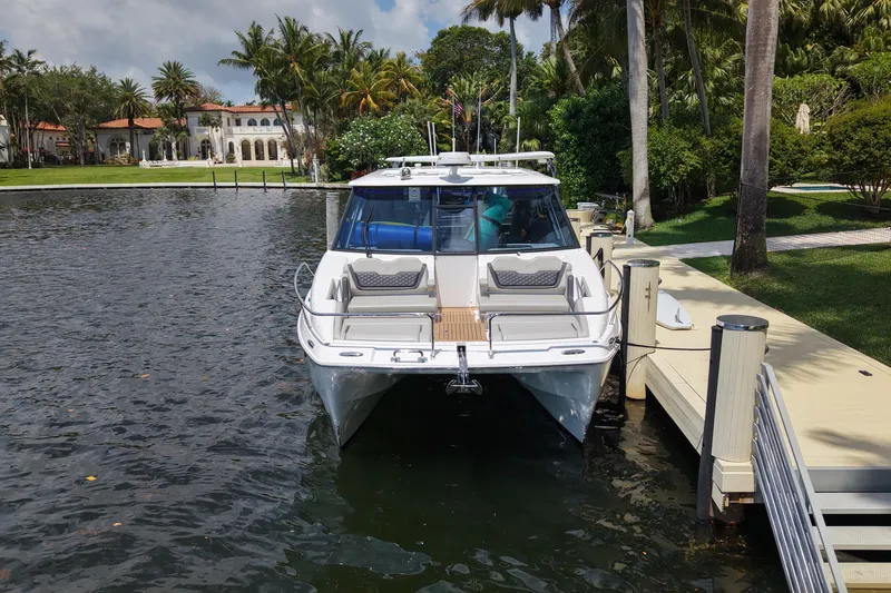 Slide: The Image of 2025 Aquila 36 Sport yacht docked by a lush waterfront estate. - 3
