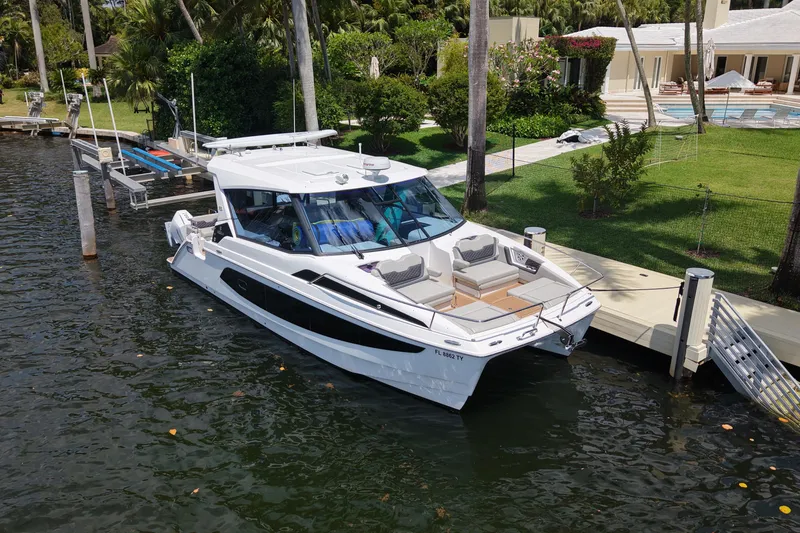 Slide: The Image of 2025 Aquila 36 Sport yacht docked by a luxurious waterfront property. - 4