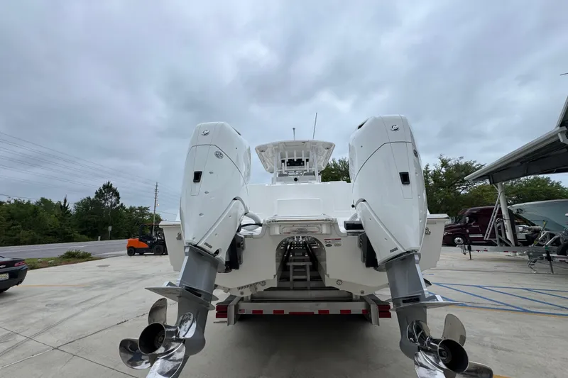 Slide: The Image of 2026 Caymas 34 CT boat with dual outboard engines on a trailer, under cloudy skies. - 14