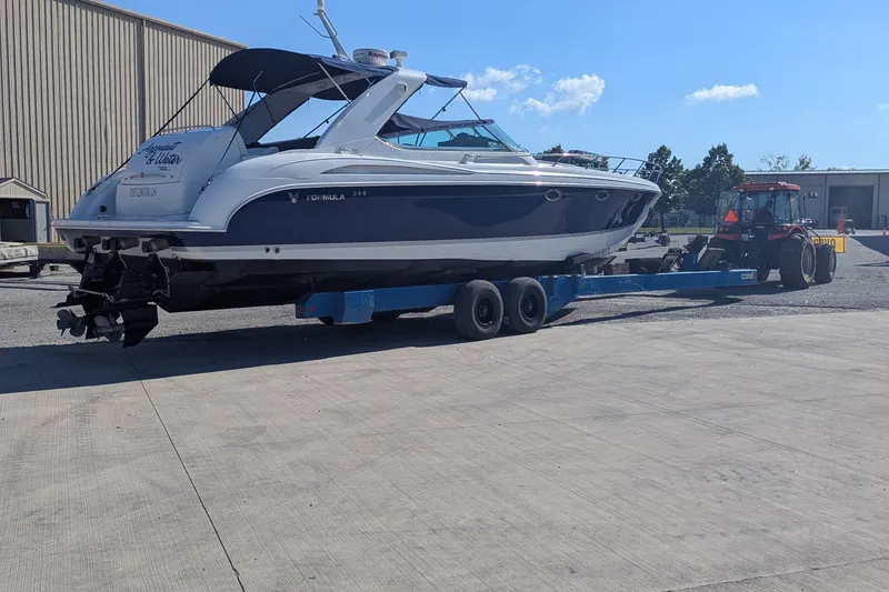 Slide: The Image of 2004 Formula 400 Super Sport boat on trailer, towed by a tractor in a marina setting. - 2