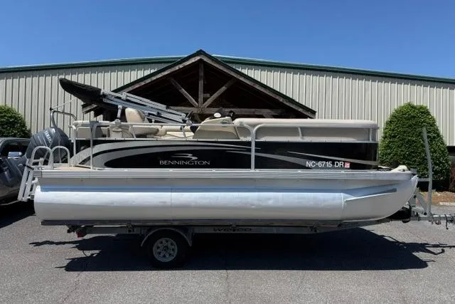 The Image of 2010 Bennington 20SLi pontoon boat on trailer, parked outdoors under clear blue sky. - 1