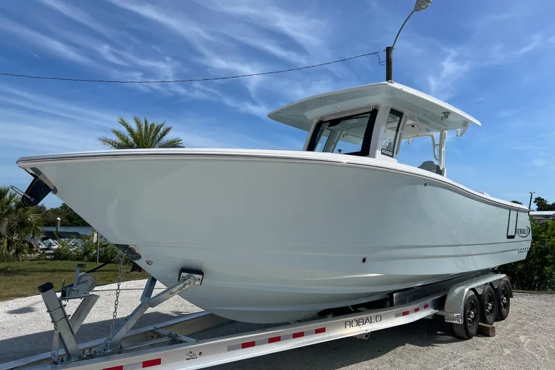 The Image of 2026 Robalo R300 Center Console boat on trailer, under clear blue sky. - 1