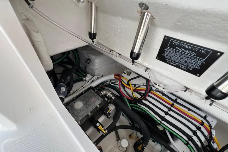 Slide: The Image of Engine compartment of 2026 Robalo R300 Center Console with wiring and oil discharge warning. - 12
