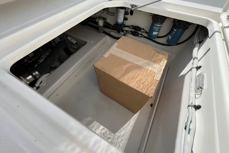 Slide: The Image of Storage compartment of 2026 Robalo R300 Center Console with a cardboard box inside. - 20