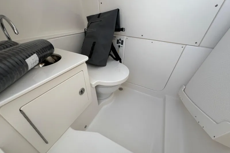 Slide: The Image of Interior of 2026 Robalo R300 Center Console boat, featuring a compact bathroom area. - 38