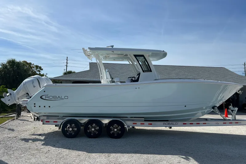 Slide: The Image of 2026 Robalo R300 Center Console boat on trailer, side view, under clear blue sky. - 6