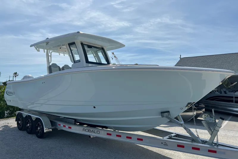Slide: The Image of 2026 Robalo R300 Center Console boat on trailer, side view under clear sky. - 7